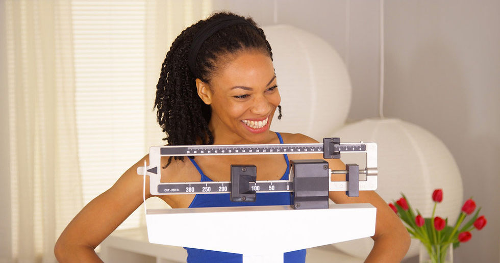 Black woman standing on a scale to monitor weight loss progress
