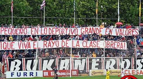 Bukaneros con una pancarta con las siguientes palabras: "Pequeño en lo deportivo, grande en valores. !Qué viva el Rayo de la clase obrera¡