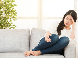 A woman obvisouly in pain on a couch.