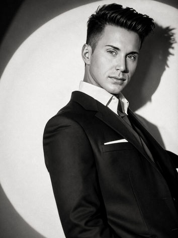Black-and-white portrait of Waymon Hudson, composer and creator of Speakeasy, in a tailored suit, dramatically lit.