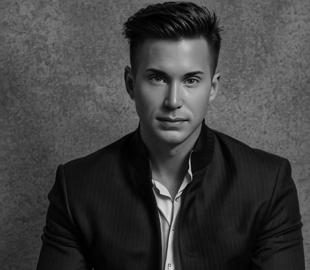 Black and white headshot of Waymon Hudson in a pinstripe jacket, framed by a textured wall. A serious and focused portrait of a bold creative leader who brings emotional connection to marketing strategy.