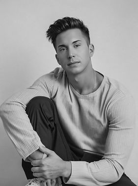 Black-and-white seated portrait of Waymon Hudson, queer memoirist and survivor of childhood trauma