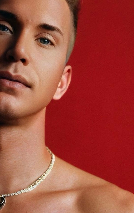 Close-up portrait of Waymon Hudson with warm red lighting, wearing a gold chain and soft expression — artistic image for Through My Skin album.