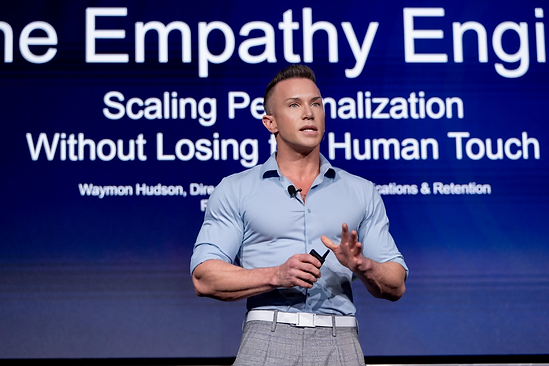 Waymon Hudson presenting on stage, gesturing, with his talk title slide behind him reading The Empathy Engine: Scaling Personalization Without Losing the Human Touch.