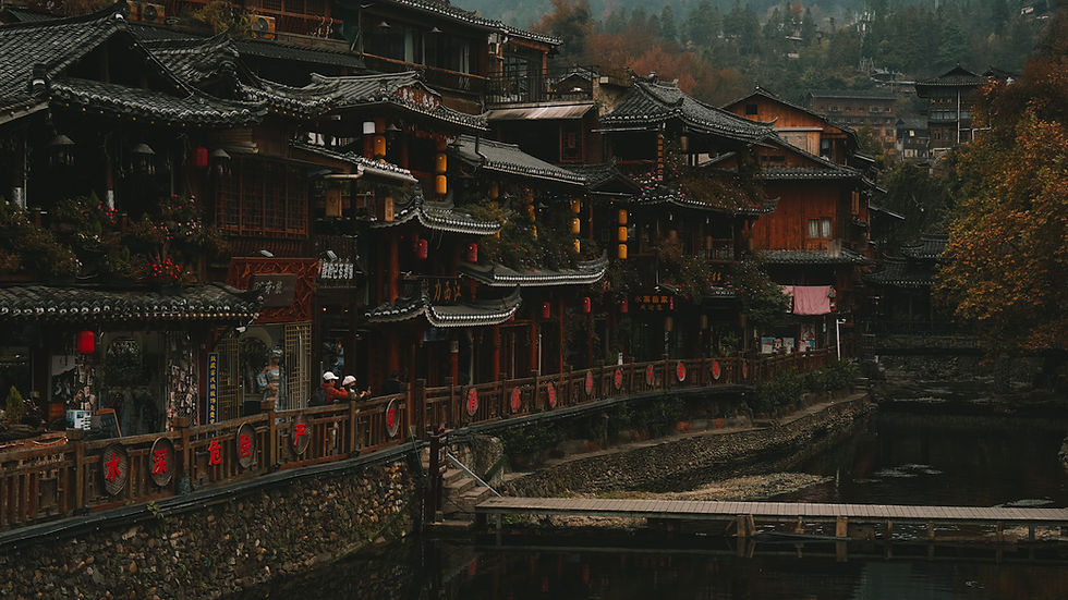 View of traditional wooden buildings by river from Wind and Rain Bridge in Xijiang Qianhu Miao Village, Guizhou, China