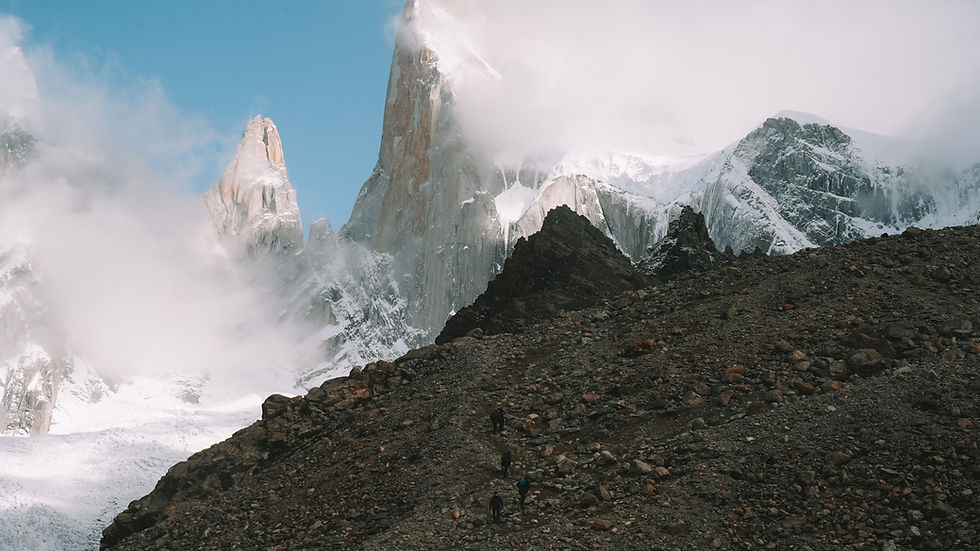 View of hikers beneath towering mountain peaks from the trail to Laguna de los Tres in Los Glaciares National Park in Argentine Patagonia