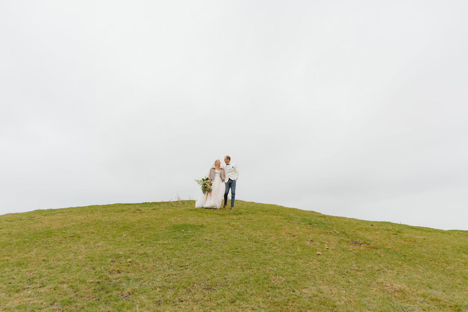 An elopement couple walking down a hill Mt. Paradise in Mouse Point, New Zealand
