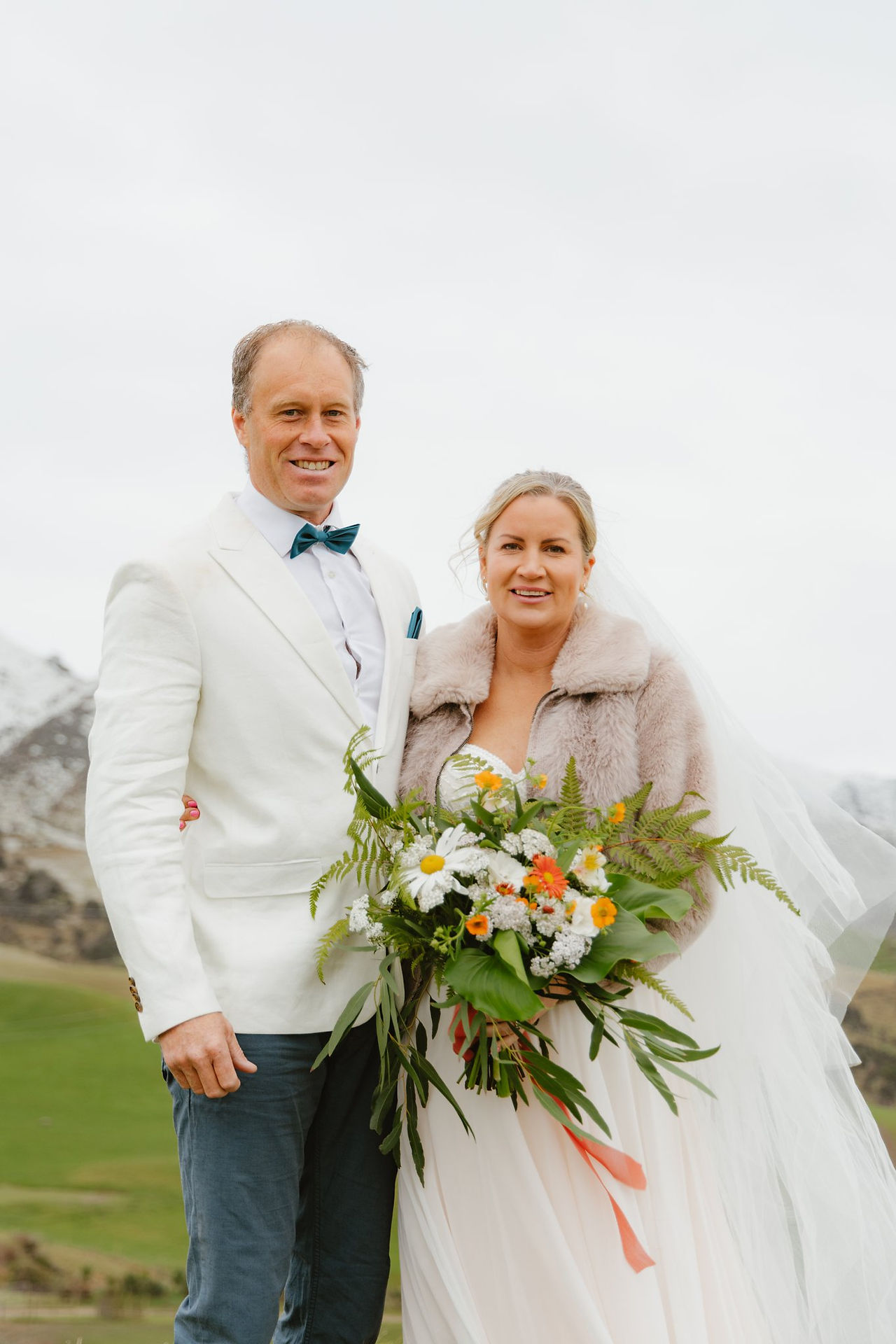 An elopement couple looking and smiling at the camera Mt. Paradise in Mouse Point, New Zealand