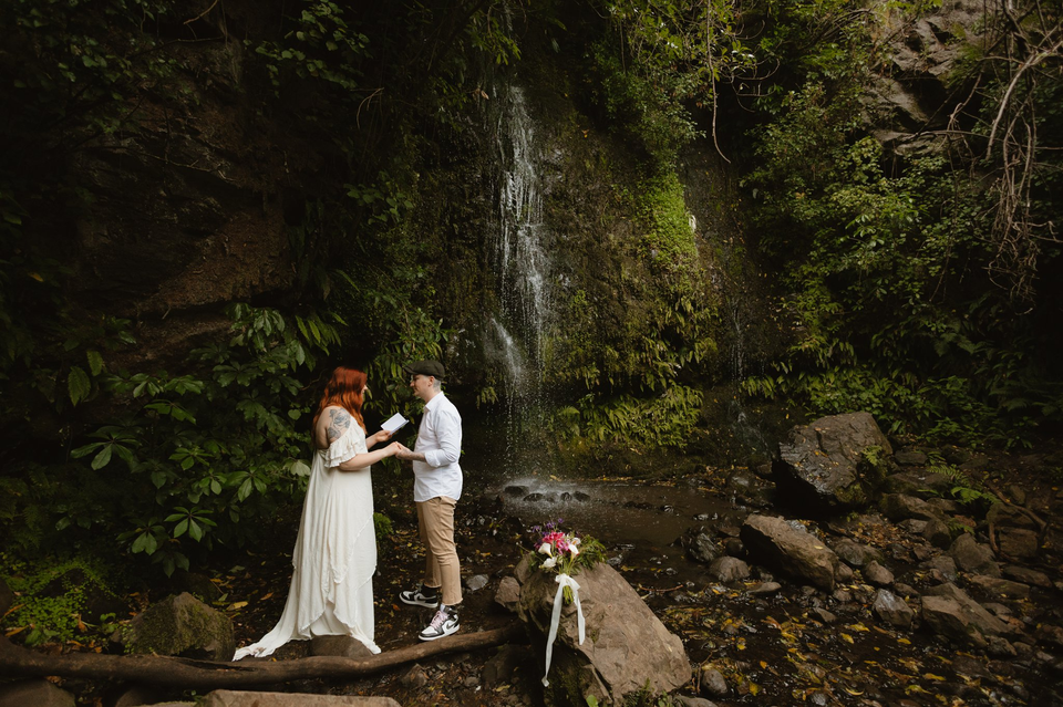A couple standing next to a waterfall in Akaroa while Eloping in New Zealand _ Chaznel Photography