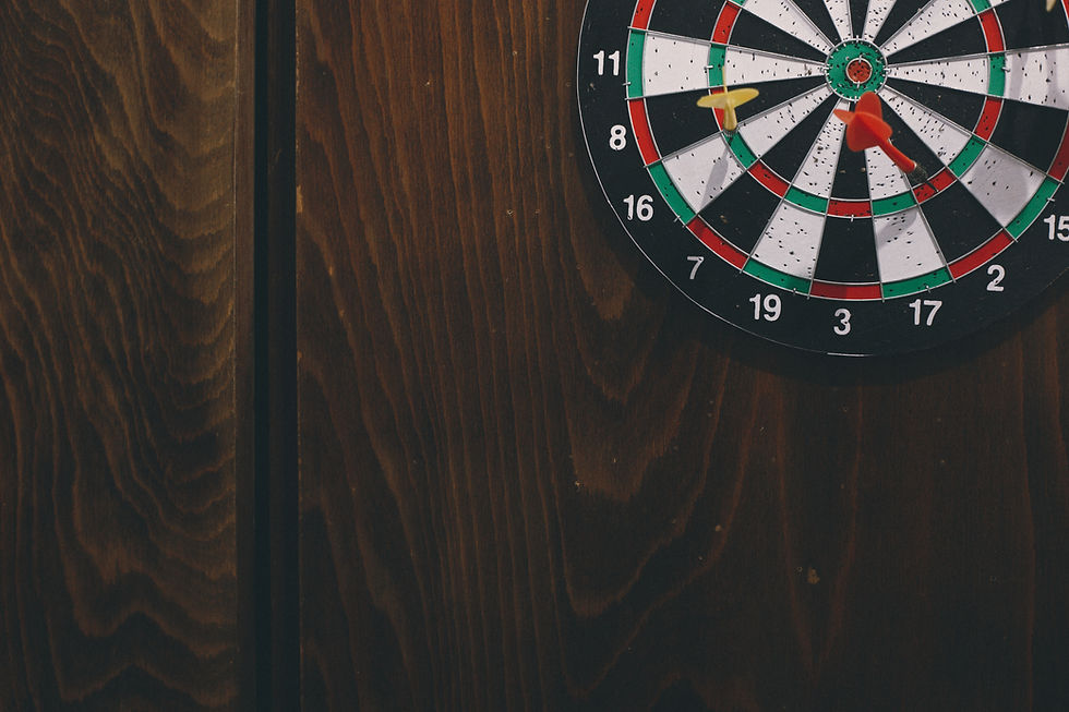 Dartboard on a dark wood wall with two darts stuck near the center, showing numbers 11, 8, 16, 19, 17, and 15.