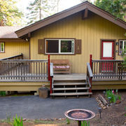 Exterior of a mountain cabin surrounded by decks and a bench overlooking a garden.
