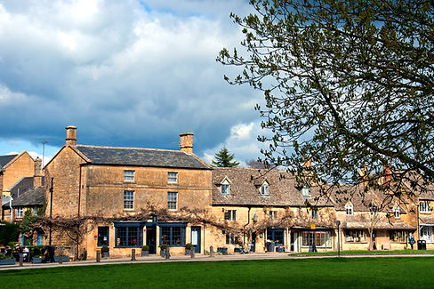 A charming Cotswolds village, Broadway, with honey-stone cottages and vibrant gardens, showcasing its timeless beauty and quaint high street.