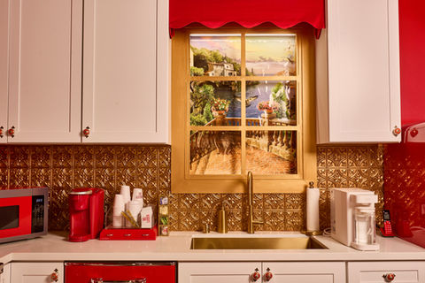 Luxury pinup-inspired French kitchen set in Los Angeles photo studio featuring red and gold interiors, Big Chill retro appliances, black and white checkered floors, burlesque wallpaper, Old Hollywood vanity lights, and a 1950s-style red and gold dining area.
