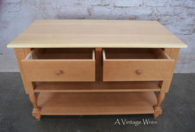 New Hampshire made solid hardwood kitchen island. The island has 2 dovetailed drawers which are open to show the depth of the drawer's interiors. The island also has 2 shelves. The legs are square turned.
The wood is a light color on the top and slightly darker on the base.
The drawer fronts are flat panel with a round wood knob.