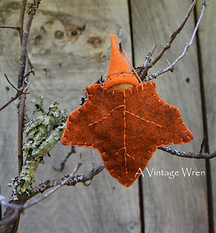 wool felt maple leave ornament with wood peg doll gnome in an orange cap 