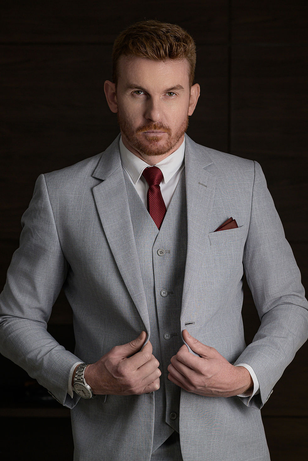 Homem de terno cinza claro fotografado com luz lateral difusa e com fundo escuro