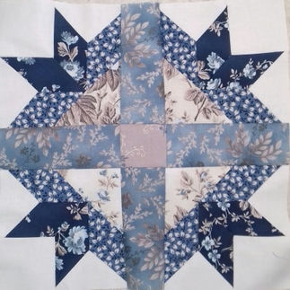 Goose Track block in blue and cream flowery fabric.