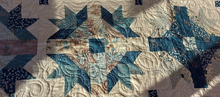 My finished Good Life Quilt close-up showing blue, cream and beige flowery fabrics.