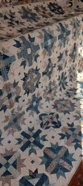 My finished Good Life Quilt showing blue, cream and beige flowery fabrics.