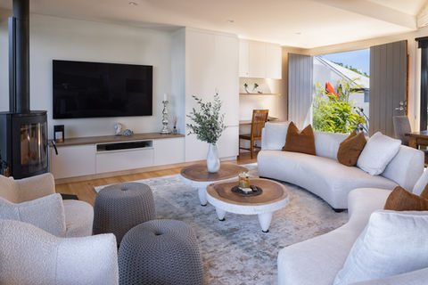Modern bright living room with white sofas, fireplace, and open doors.
