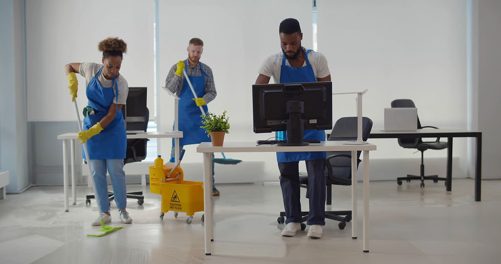 Eine multikulturelle Reinigungstruppe in einheitlicher Arbeitskleidung verwendet Reinigungsgeräte, um das Büro zu säubern