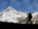 Hiker silhouetted against a snowy mountain peak