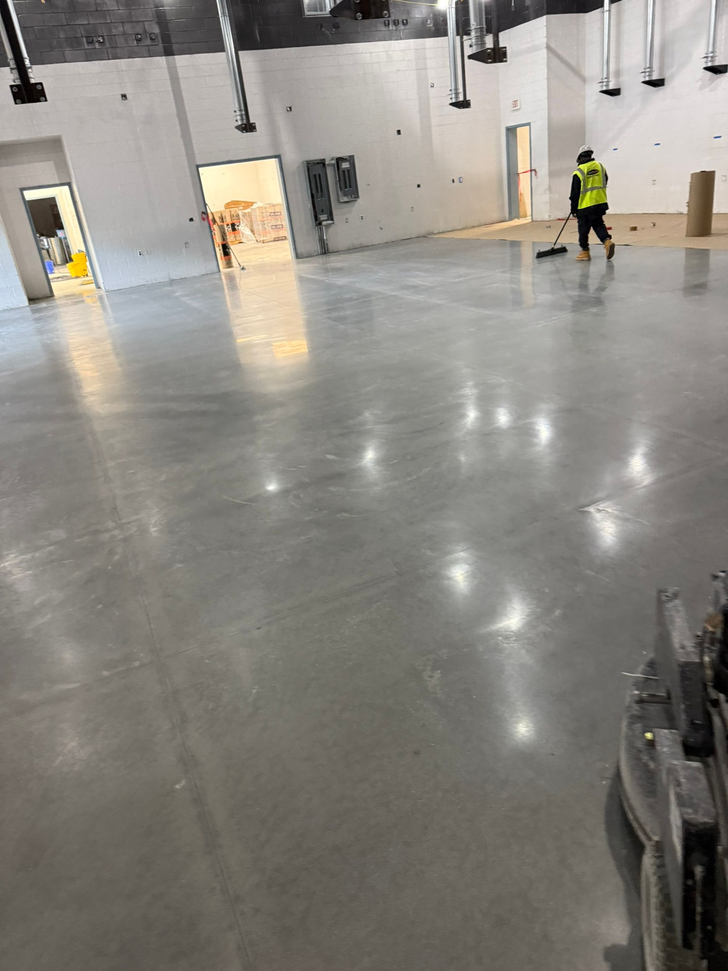 Final stage of concrete polishing showing reflective, smooth floor finish across large commercial area.