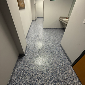 Completed epoxy flake floor in a commercial hallway, featuring a smooth, blue-gray decorative finish with clean base trim and bright lighting.