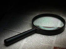 a magnifying glass laying on top of a book while it magnifies some of the wording that is unreadable