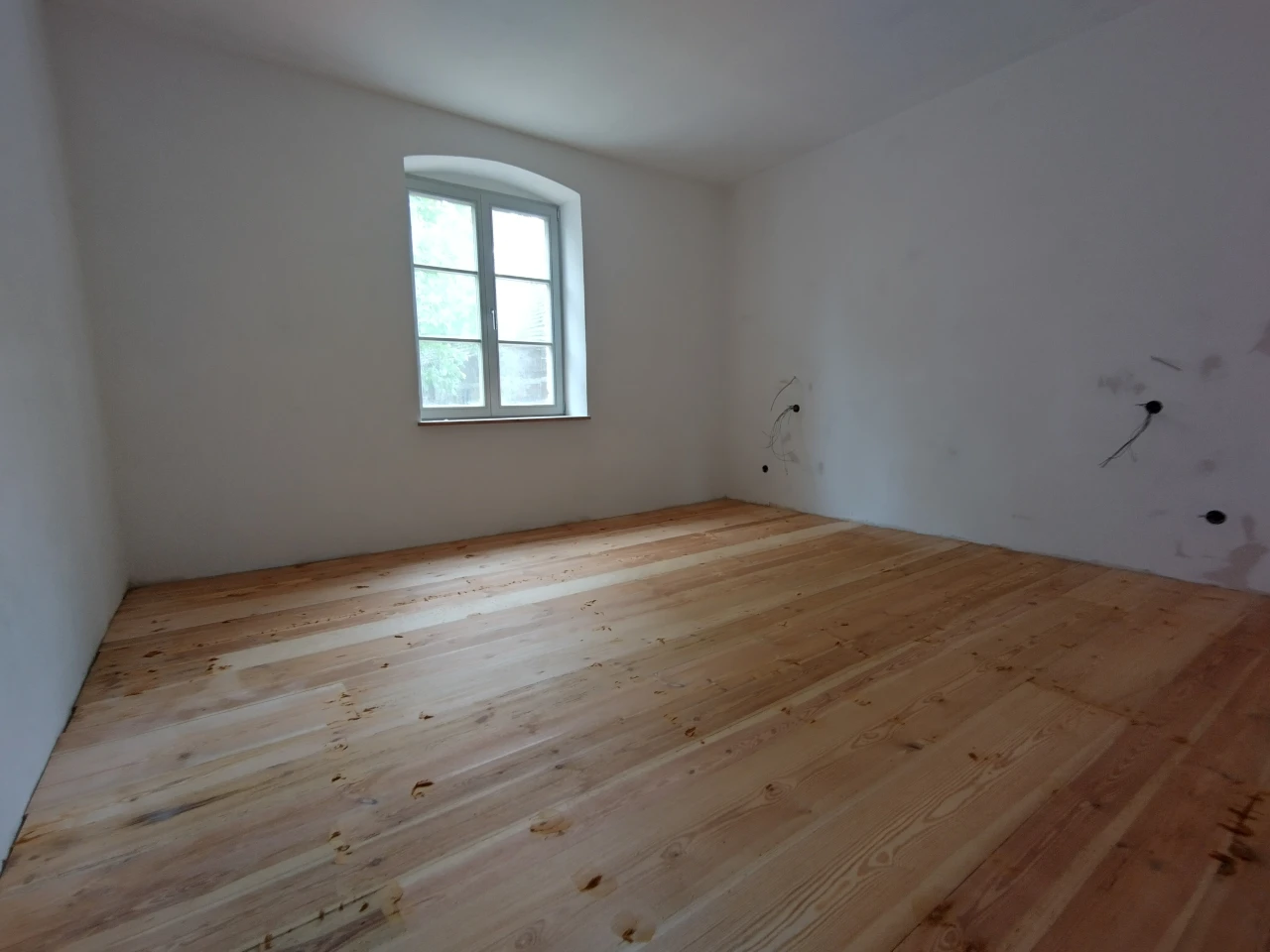 Einfaches Zimmer in weiß gehalten mit Holzdielenfußboden