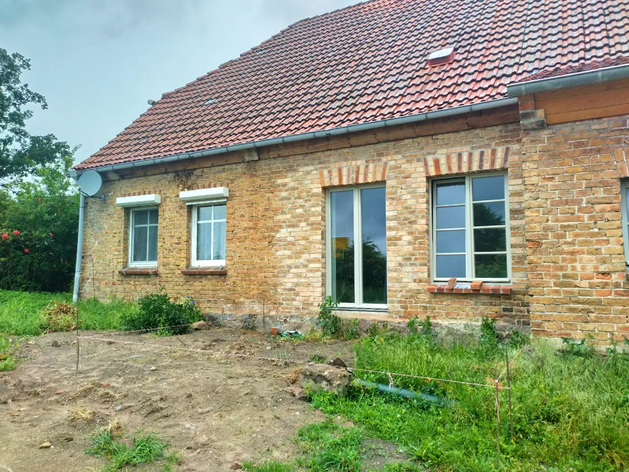 Backsteinfassade mit sehr unterschiedlich schattierten Ziegeln, große Fensteröffnungen