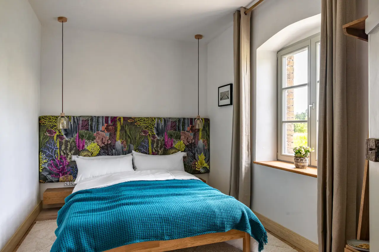 Modernes Schlafzimmer im Bauernhausstil, bunt gemustertes Kopfteil, Holzbett.