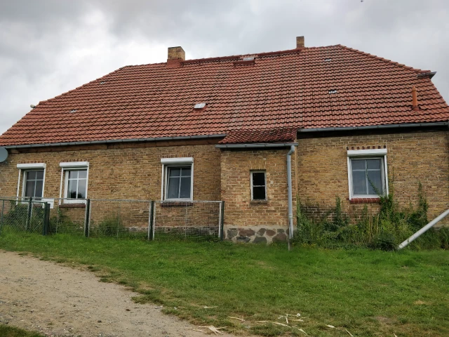 Hausansicht mit Kunststofffenstern und altem Zaun