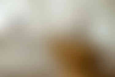 two parents embrace as the dad holds their newborn in his arms in a room with antique furniture