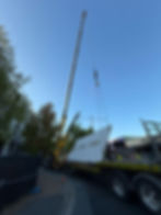 Yellow crane lifting a large white panel at a project site.