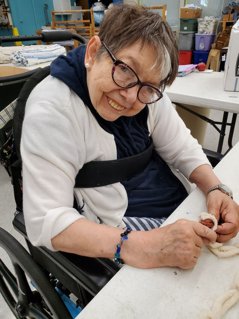 A participant smiles as she sews together a rug