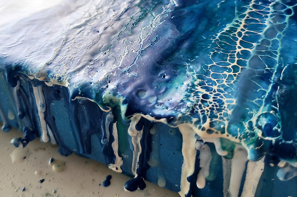 Close-up view of a wooden panel with layers of melted wax and vibrant pigments