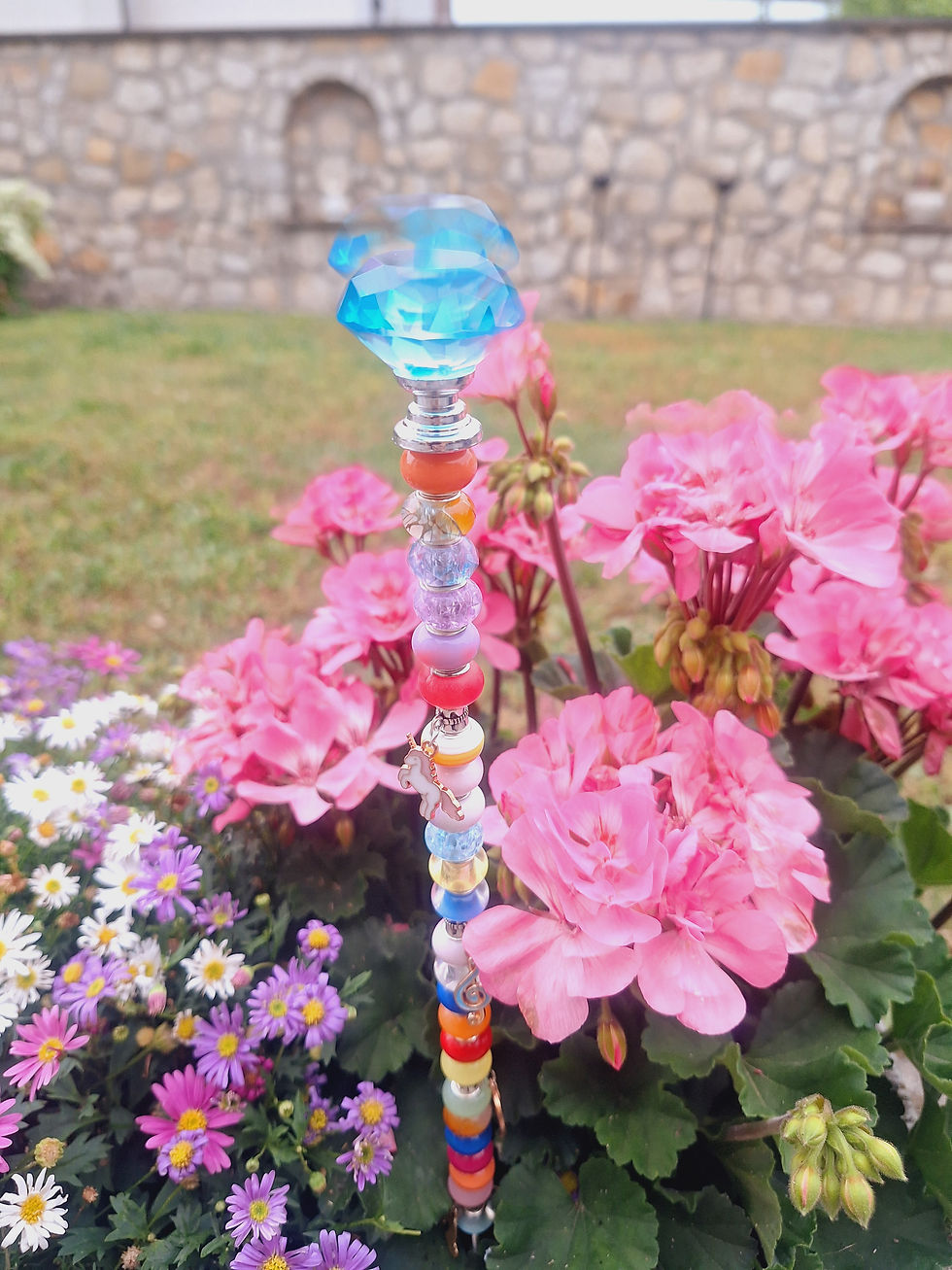 Miniaturbild: Bunter Gartenstecker mit Acryl Perlen zwischen rosa Geranien und kleinen Blüten vor Steinmauer.