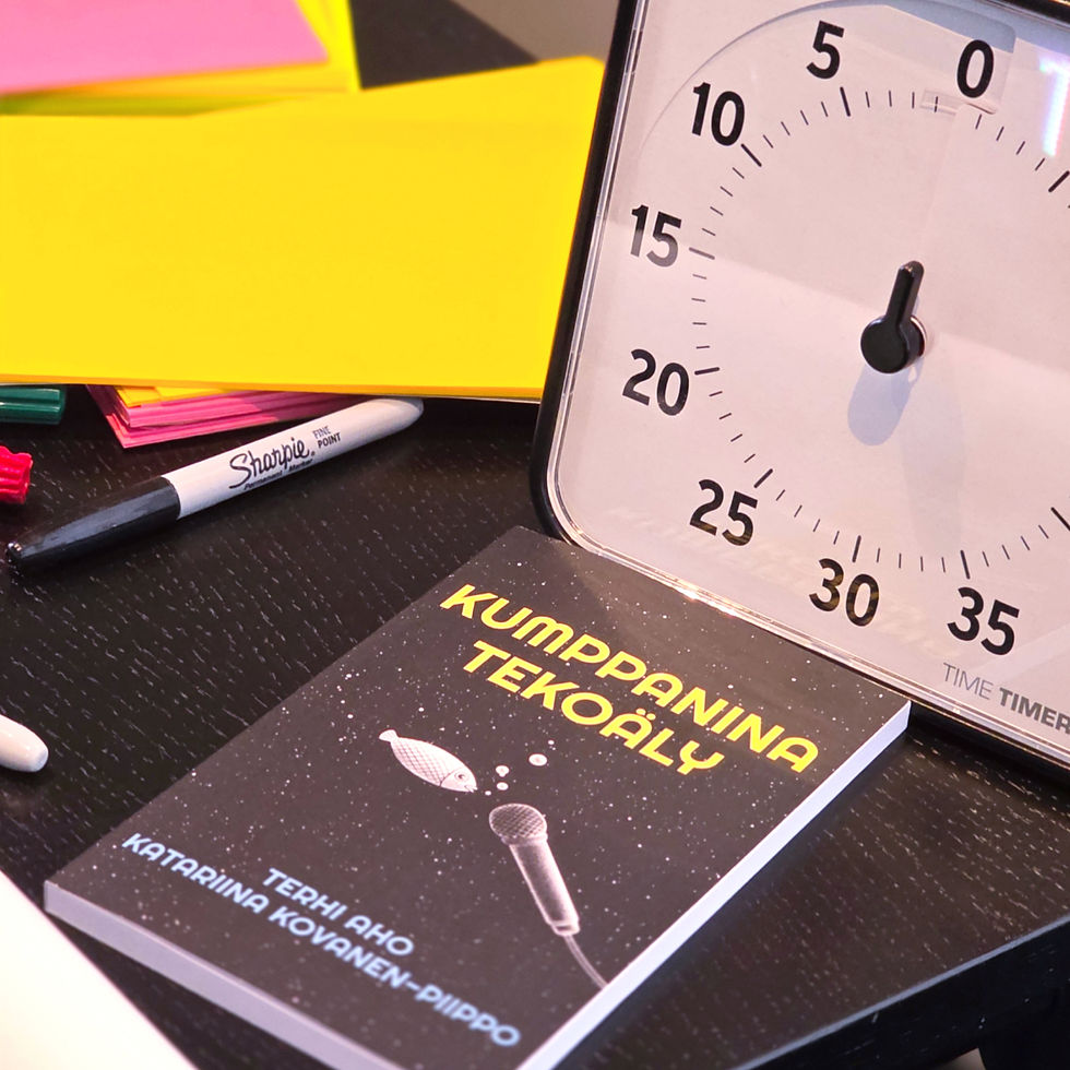 Työpöydällä kumppanina tekoäly -kirja ja posti-it lappuja, ajastin ja sharpie-kynä