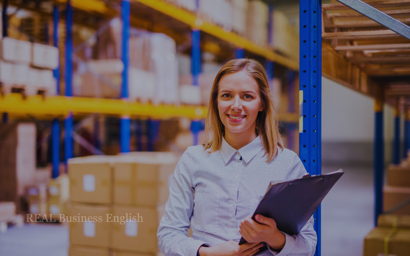 Warehouse manager holding a clipboard in a distribution center during Business English speaking practice