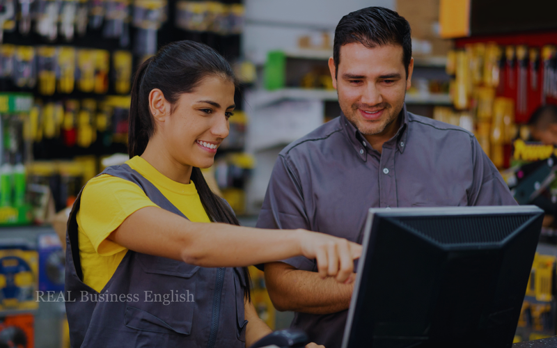 Hardware store employees reviewing information at a checkout computer while preparing for a new same-day delivery service.
