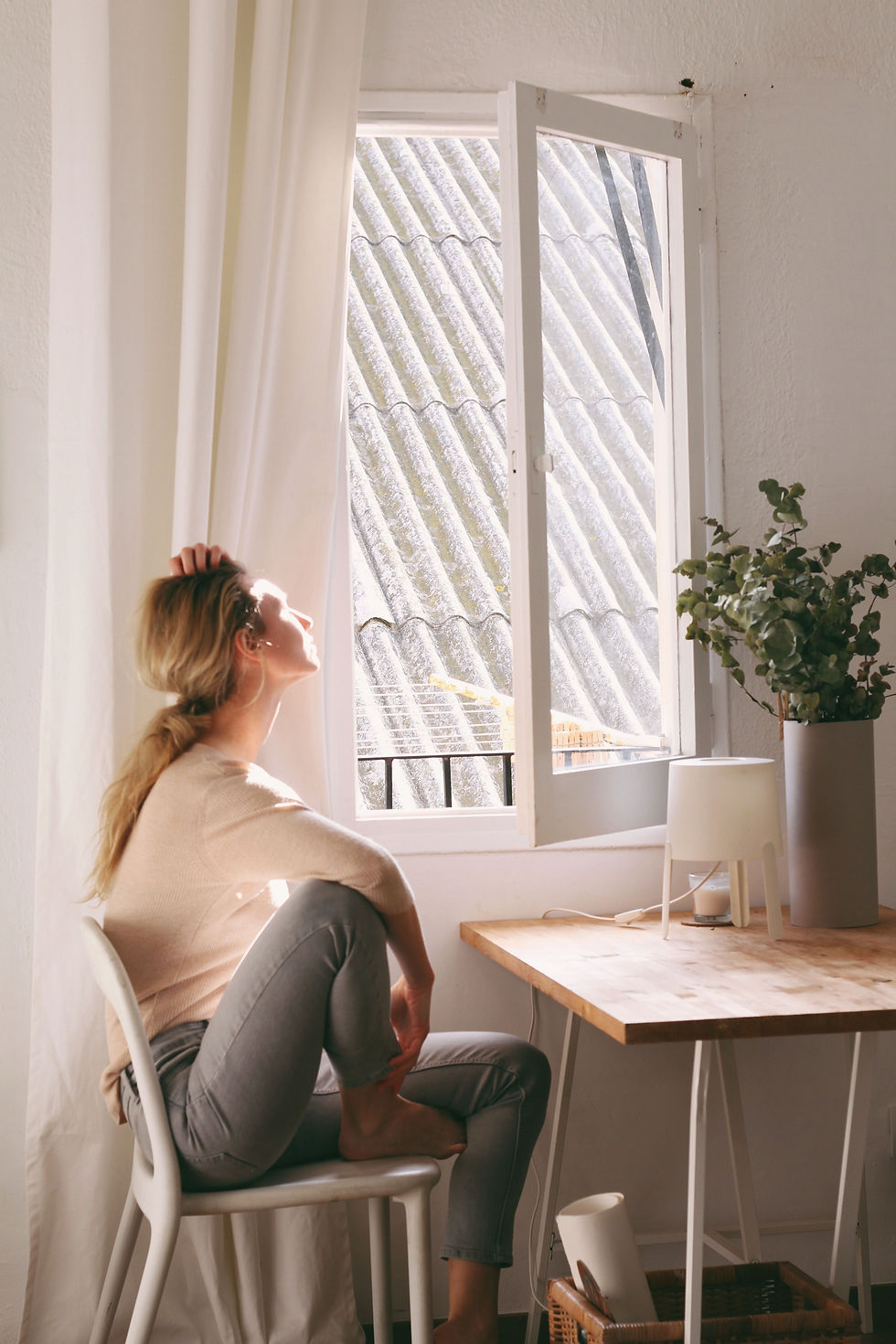 woman sitting by open window in soft natural light