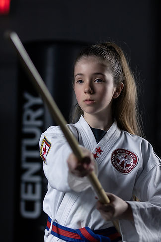 Girl training with bo staff at NextGen Martial Arts after school program Burlington - ITF Taekwondo weapons training