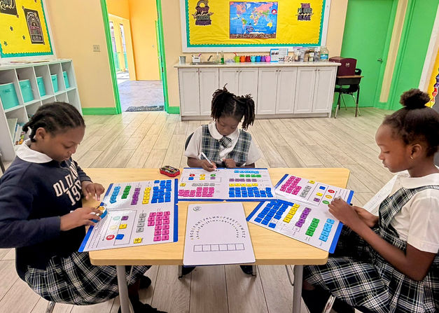 Three Adelaide Primary School students in the Adelaide Auxiliary Learning Support Programme use colorful letter tiles and word mats to build and read digraph words.