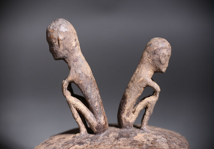 Two seated anthropomorphic figures facing away from each other