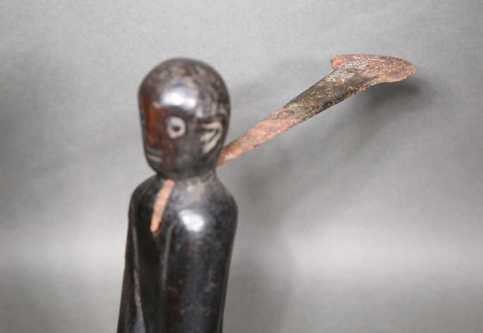 A detailed shot that focuses on the metal blade attached on the anthropomorphic carving
