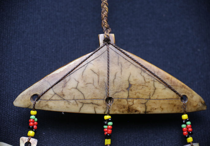Strings with beads are attached to the triangular shell pendant