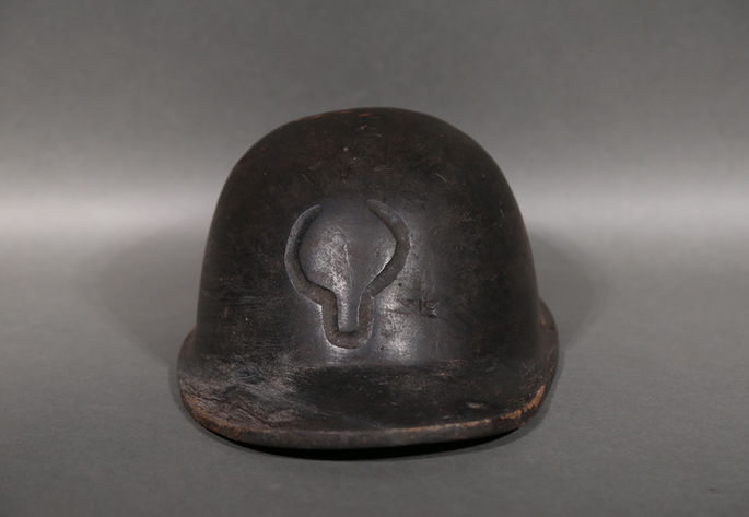 A wooden soldier’s hat with etched head of a carabao figure at the middle