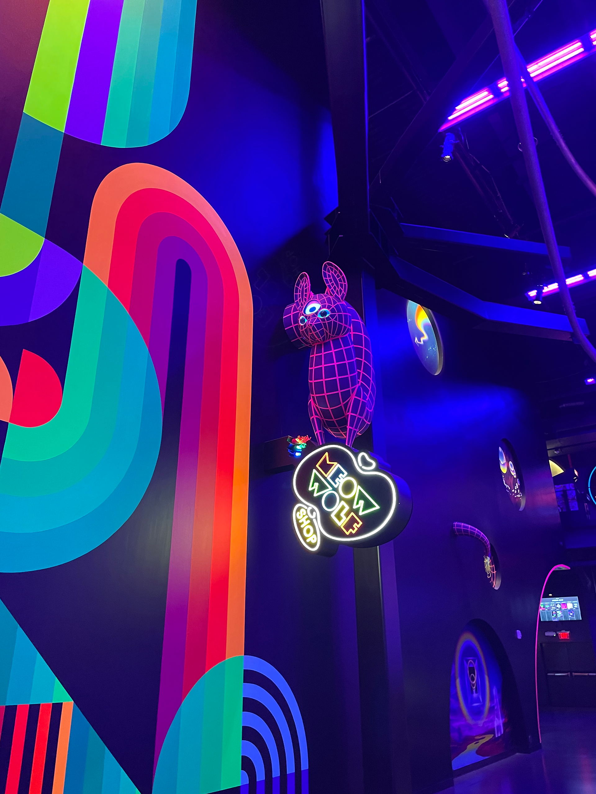 Neon curved lines and a creature with a neon sign that says 'Meow Wolf'