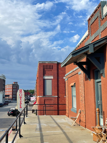 Brick buildings with a sign that says "Hotel" and a blue sky with some clouds covering.